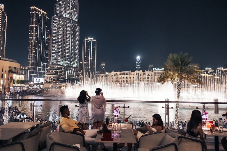 Cặp đôi nâng ly bên bàn ăn tối nhìn ra đài phun nước Dubai và tháp Burj Khalifa