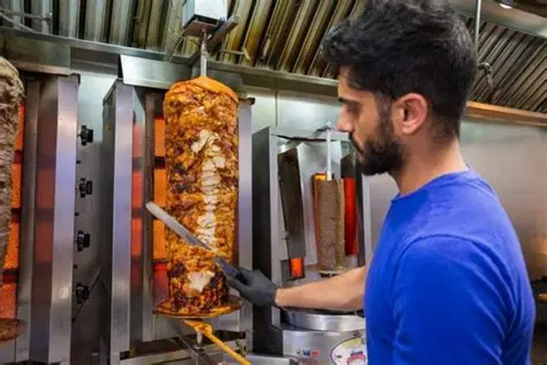Nhân viên thái thịt shawarma từ xiên quay tại quầy phục vụ