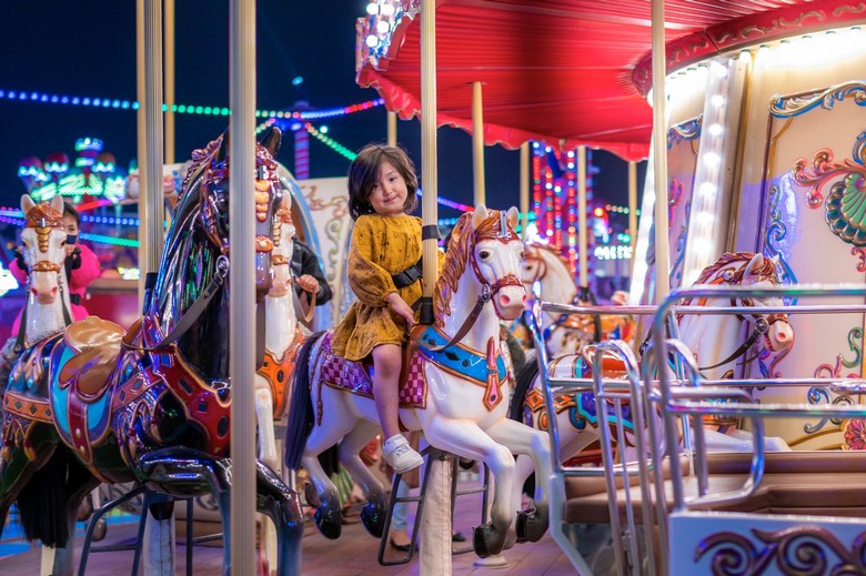 Trẻ em vui chơi tại khu Carnival với vòng quay và đèn màu rực rỡ