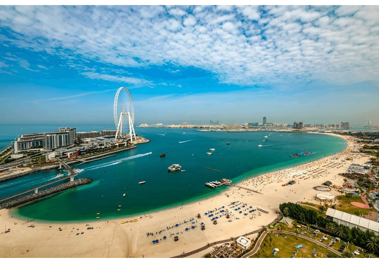 Bãi biển JBR Dubai đông vui với nền cao ốc và vòng quay Ain Dubai