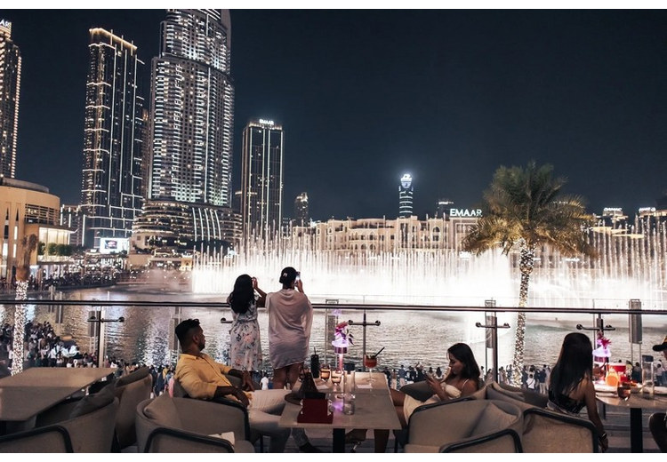 Cặp đôi nâng ly bên bàn ăn tối nhìn ra đài phun nước Dubai và tháp Burj Khalifa