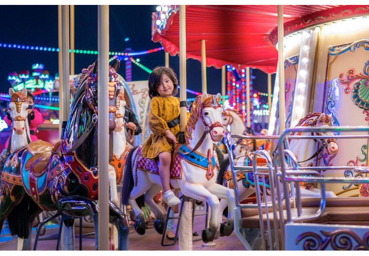 Trẻ em vui chơi tại khu Carnival với vòng quay và đèn màu rực rỡ